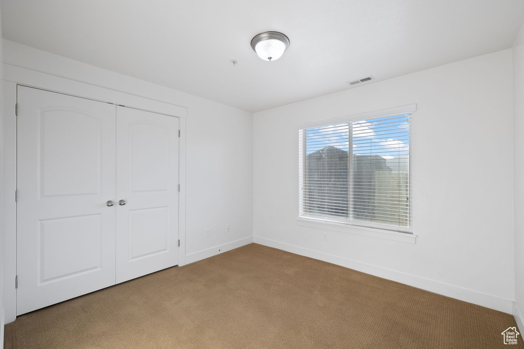 Unfurnished bedroom featuring carpet flooring and a closet