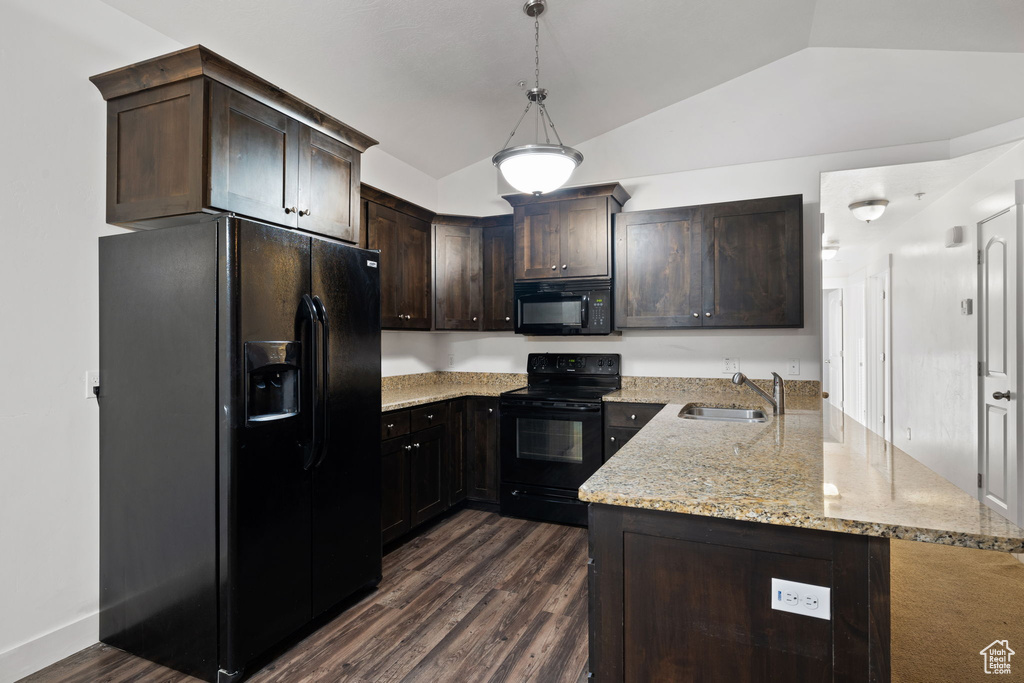 Kitchen with black appliances, kitchen peninsula, hanging light fixtures, dark hardwood / wood-style floors, and light stone countertops