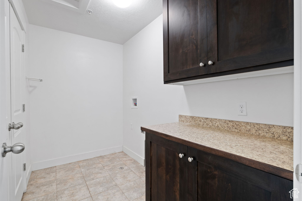 Laundry area with cabinets, hookup for a washing machine, and light tile patterned floors