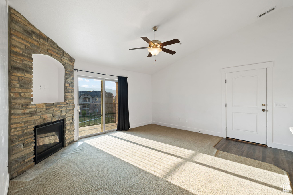 Unfurnished living room with a fireplace, ceiling fan, carpet flooring, and vaulted ceiling