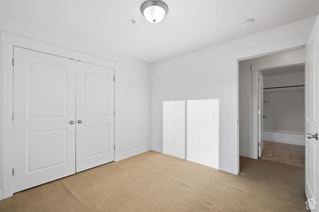 Unfurnished bedroom featuring light carpet and a closet