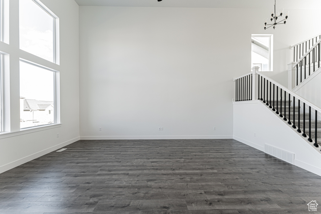 Spare room with a chandelier, a high ceiling, and dark hardwood / wood-style floors