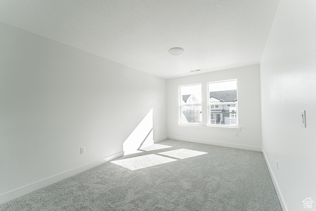 Carpeted spare room featuring a textured ceiling
