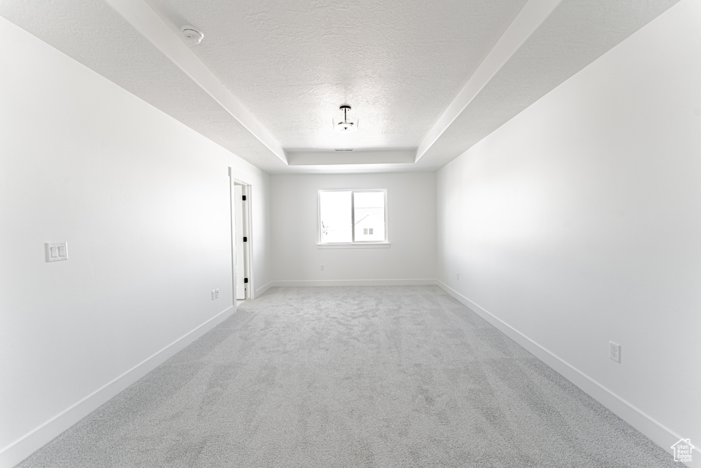 Carpeted spare room with a textured ceiling and a raised ceiling