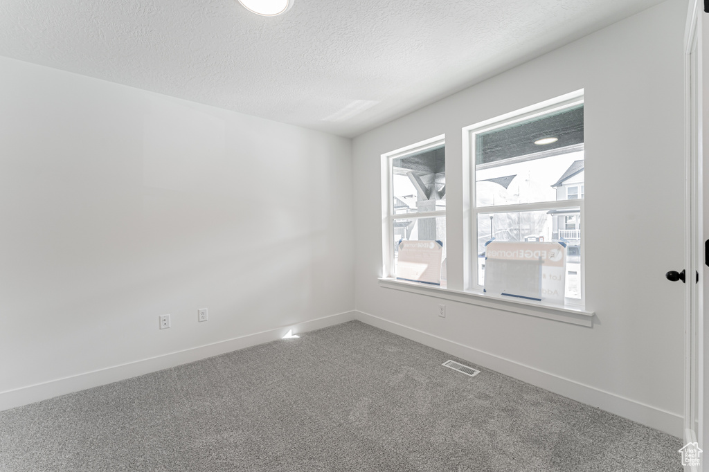 Spare room featuring carpet flooring and a textured ceiling