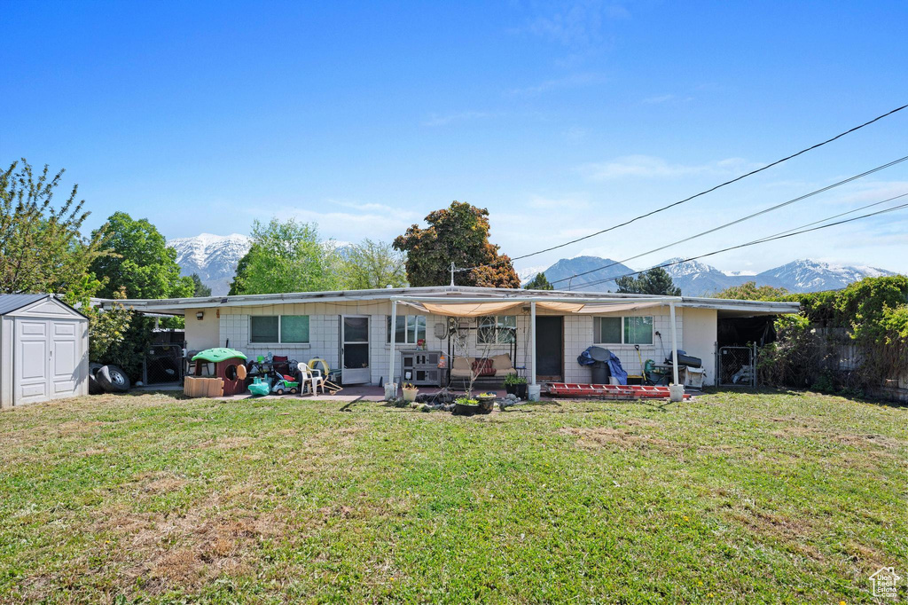 Rear view of house featuring a mountain view, a shed, and a lawn