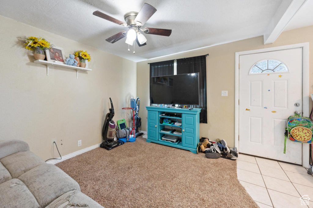 Living room with beam ceiling, a textured ceiling, ceiling fan, and light tile flooring