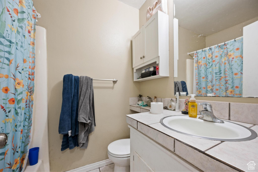 Bathroom with vanity with extensive cabinet space, tile flooring, and toilet