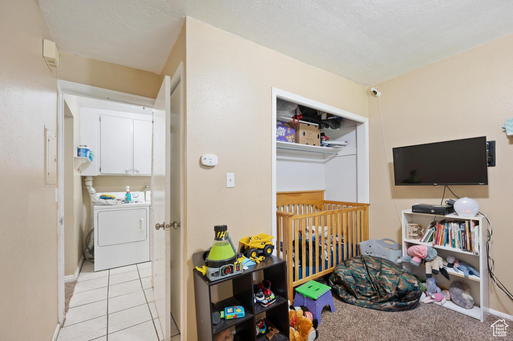 Recreation room featuring a textured ceiling, washer / dryer, and light tile floors