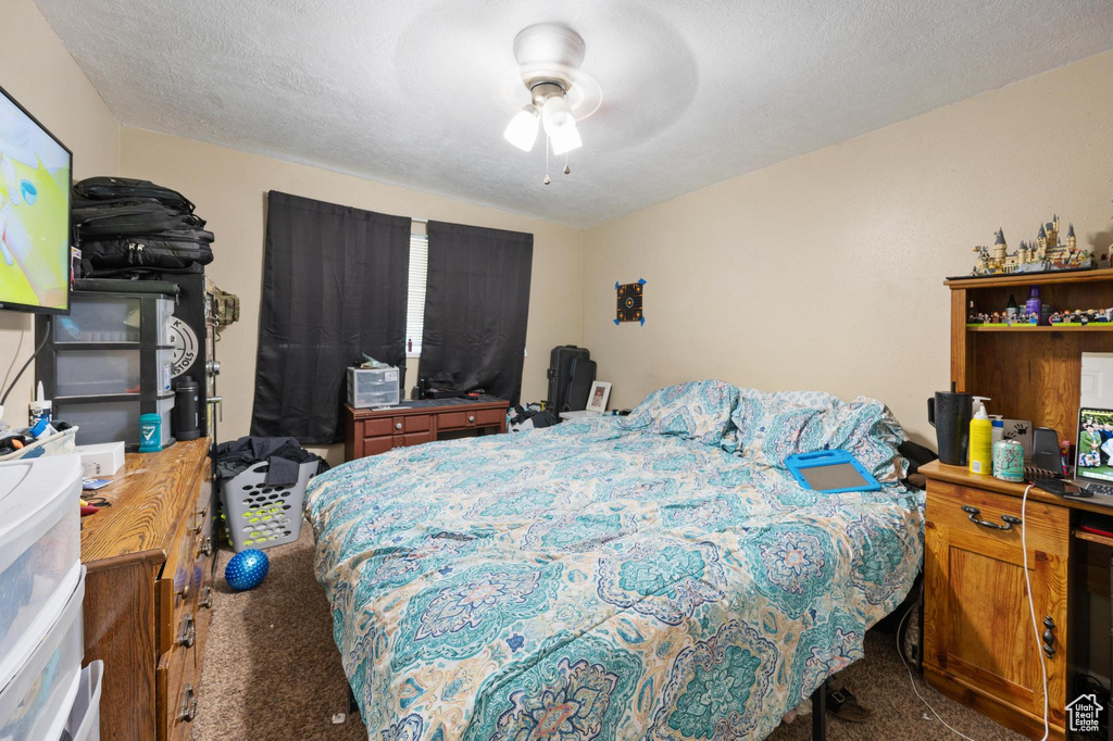 Carpeted bedroom with ceiling fan and a textured ceiling