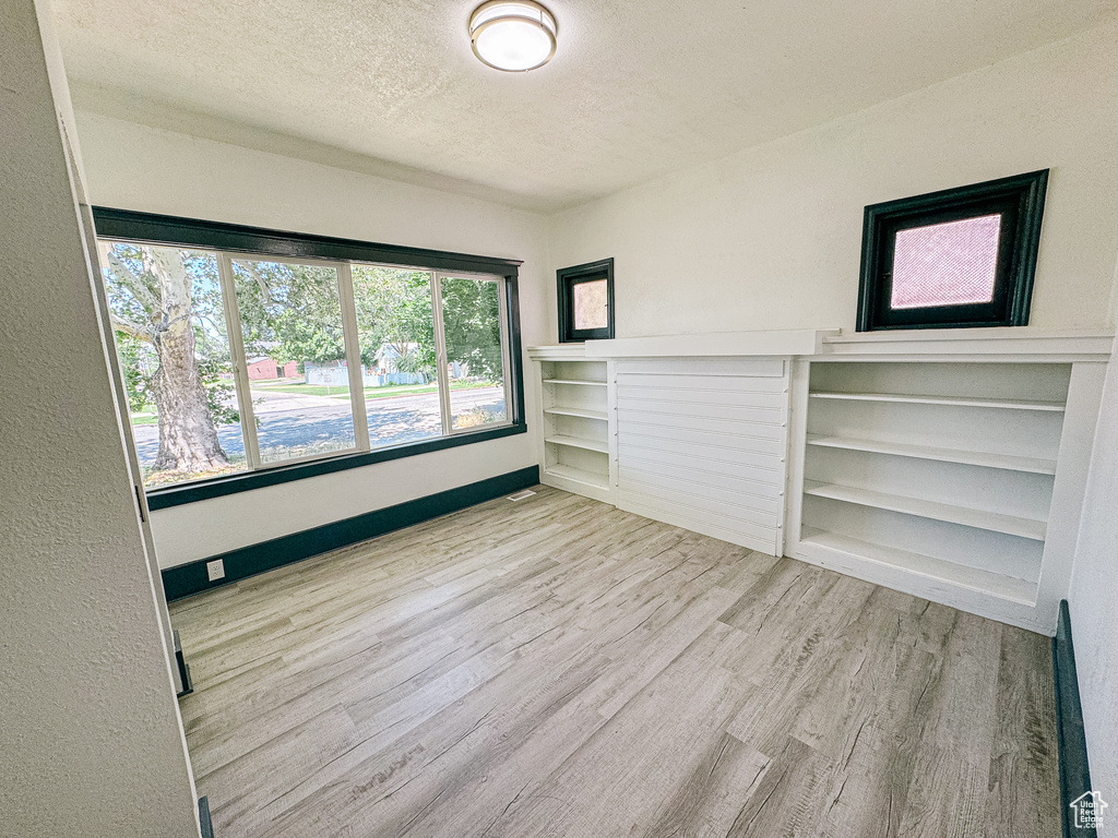 Unfurnished living room with a textured ceiling and light hardwood / wood-style floors