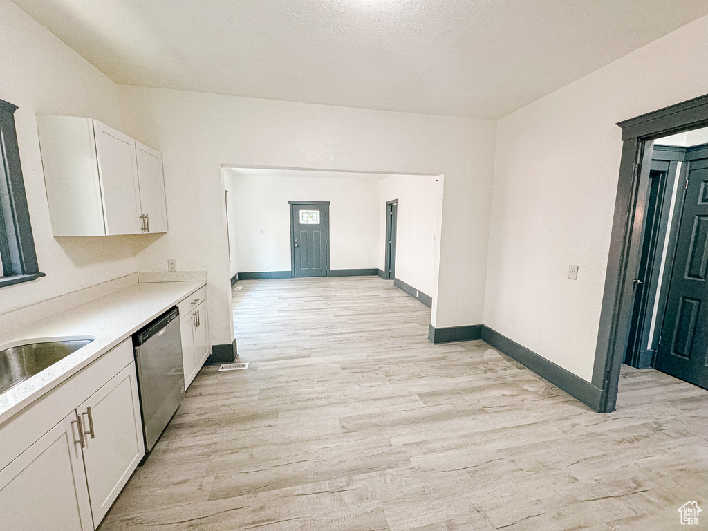 Kitchen featuring stainless steel dishwasher, white cabinets, and light hardwood / wood-style floors