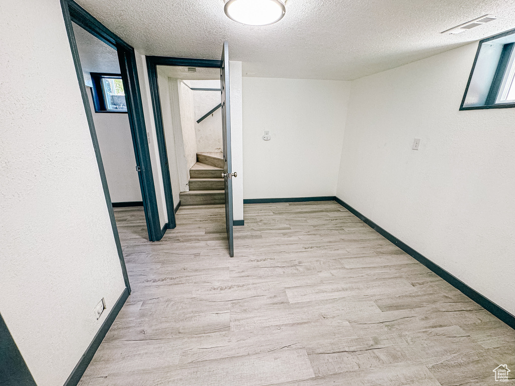 Hallway with light hardwood / wood-style floors and a textured ceiling