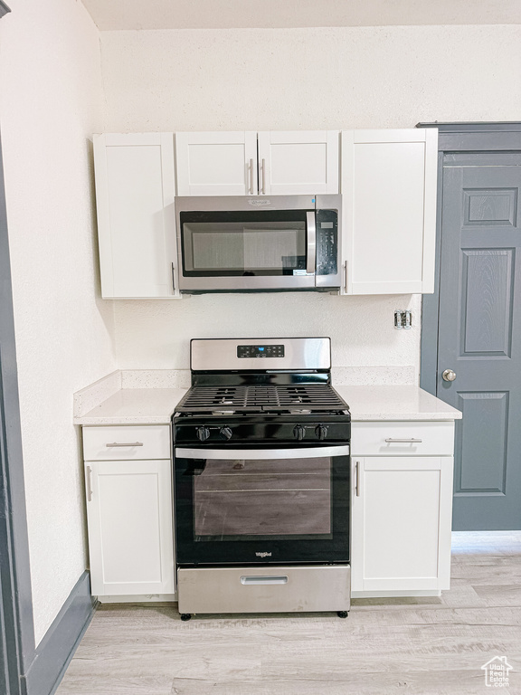 Kitchen with light hardwood / wood-style flooring, white cabinets, and stainless steel appliances