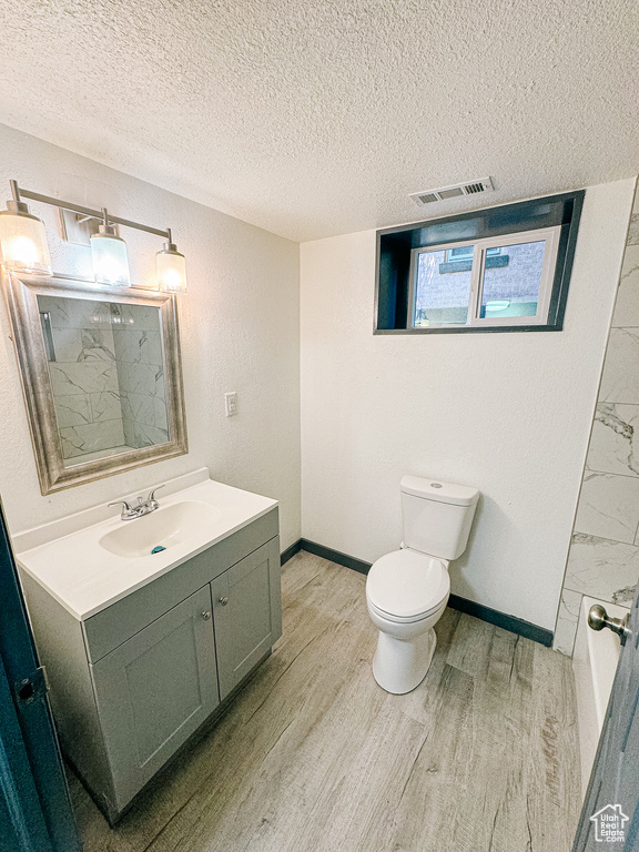 Bathroom featuring vanity, a textured ceiling, toilet, and hardwood / wood-style floors