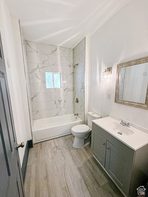 Full bathroom featuring hardwood / wood-style flooring, toilet, vanity, and tiled shower / bath