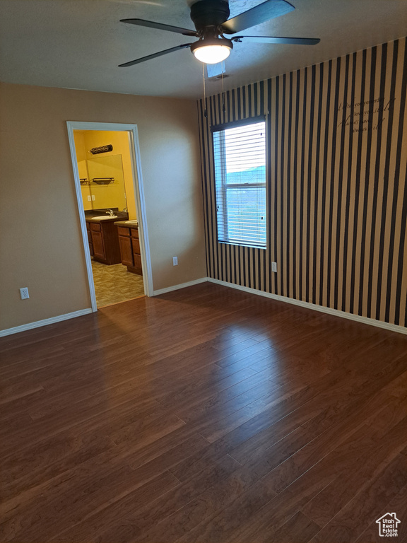 Empty room featuring dark wood-type flooring and ceiling fan