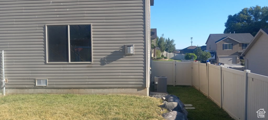 View of side of home featuring central air condition unit and a lawn