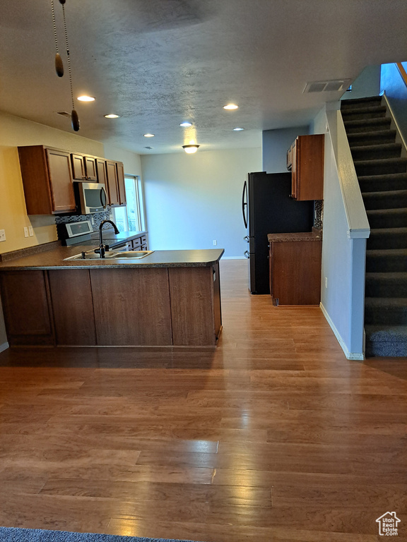 Kitchen with sink, wood-type flooring, kitchen peninsula, and range with electric cooktop