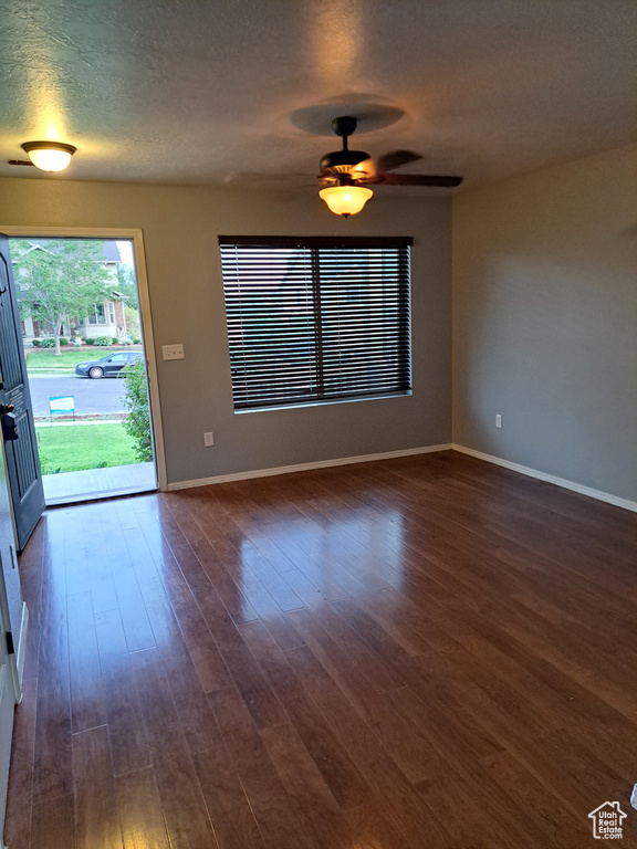 Empty room with a textured ceiling, ceiling fan, and wood-type flooring