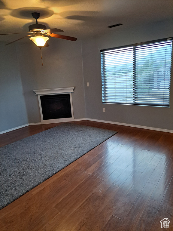 Unfurnished living room with ceiling fan and dark hardwood / wood-style floors