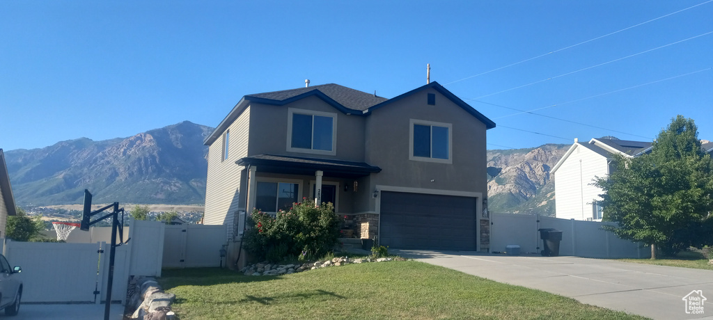 View of front of house featuring a mountain view, a garage, and a front yard