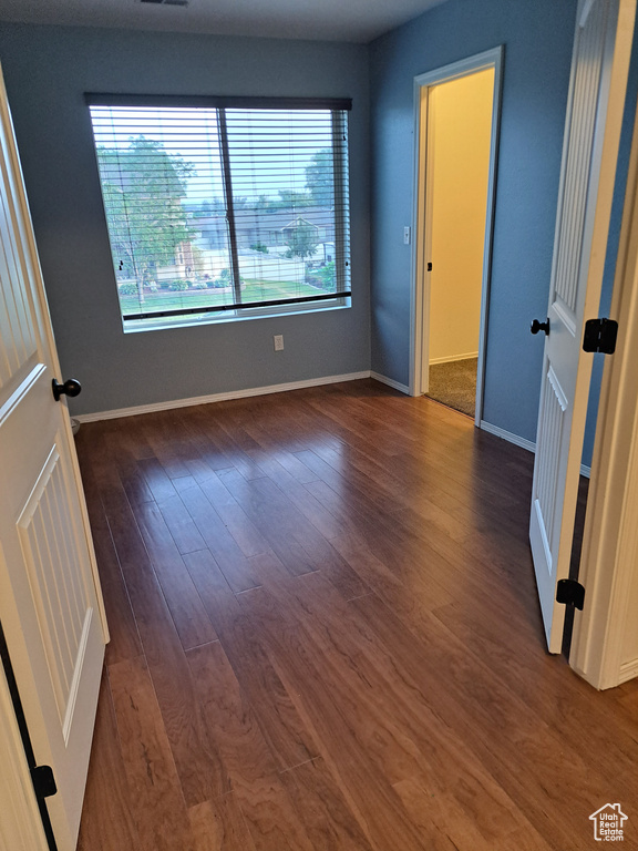 Empty room with dark wood-type flooring and a wealth of natural light