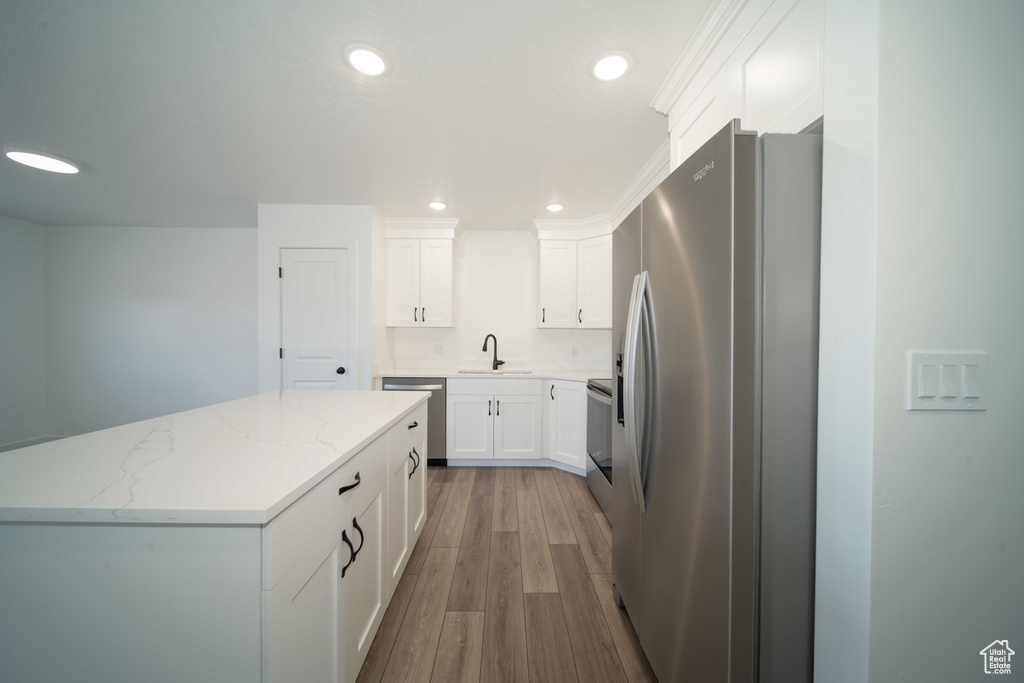 Kitchen with stainless steel appliances, light hardwood / wood-style floors, white cabinets, and sink