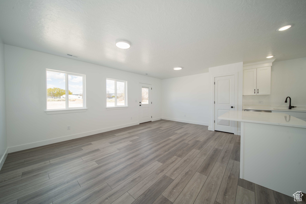 Unfurnished living room with sink and light wood-type flooring