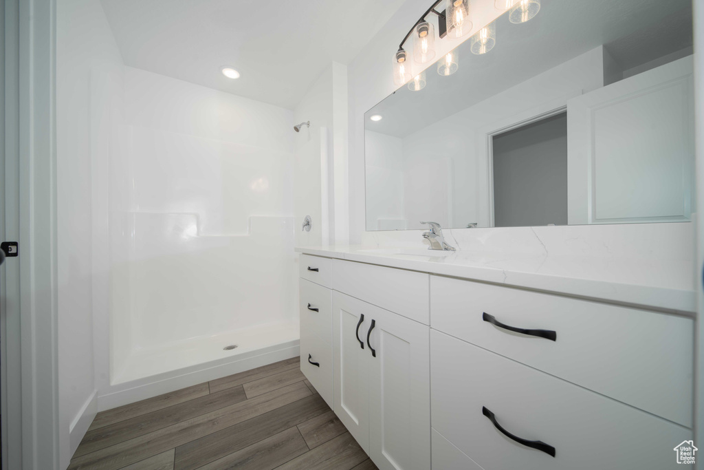 Bathroom with walk in shower, vanity, and hardwood / wood-style floors