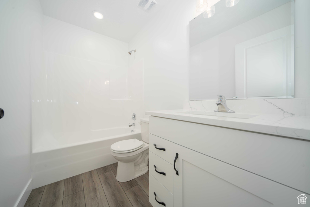 Full bathroom with hardwood / wood-style flooring, shower / bath combination, toilet, and vanity with extensive cabinet space