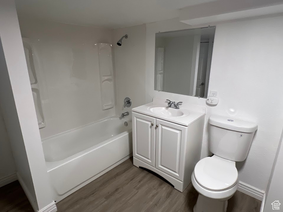 Full bathroom featuring toilet, hardwood / wood-style floors, vanity, and shower / bathtub combination