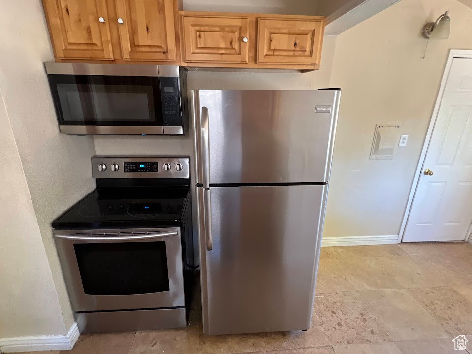 Kitchen with light tile patterned flooring and appliances with stainless steel finishes