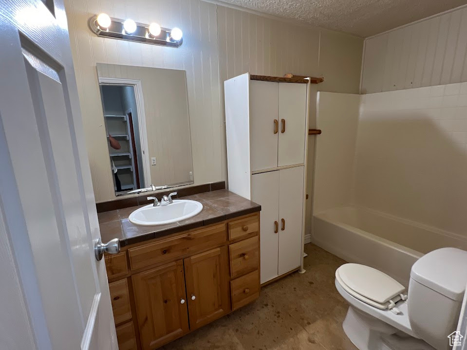 Full bathroom with shower / bathtub combination, vanity, a textured ceiling, and toilet