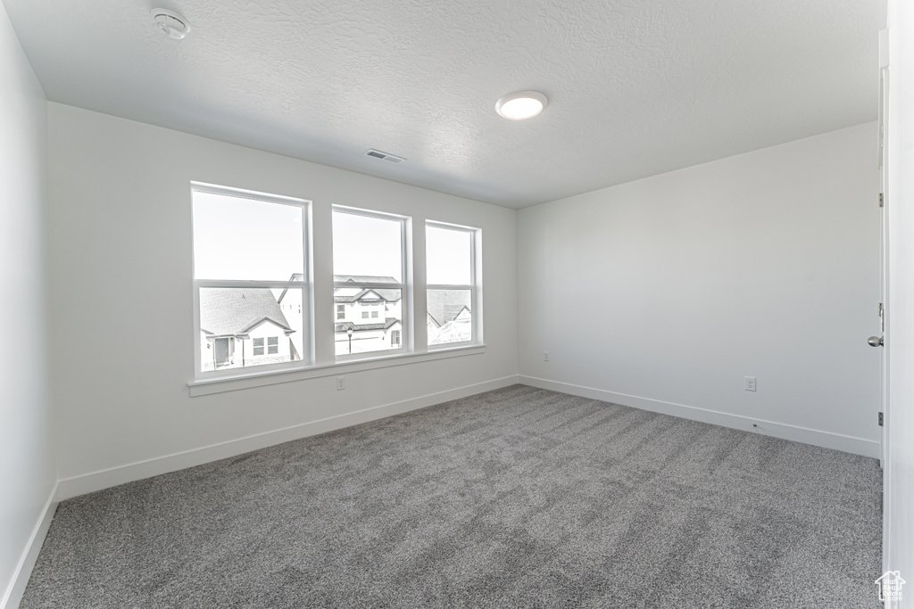 Empty room with carpet floors and a textured ceiling