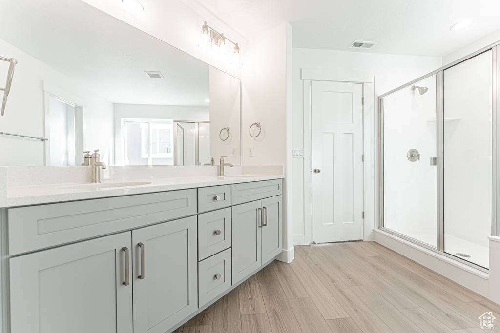 Bathroom with hardwood / wood-style flooring, a shower with shower door, and vanity