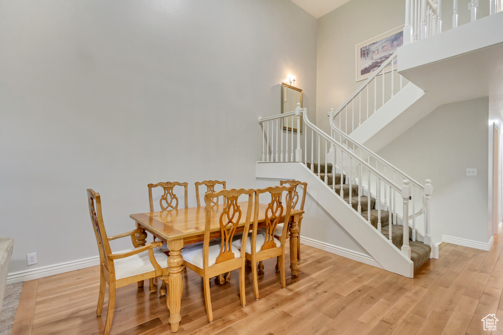 Dining room featuring light wood-type flooring and a towering ceiling