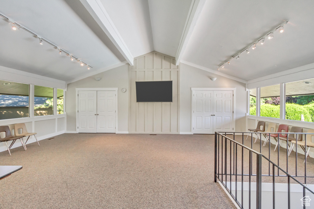 Interior space with track lighting, vaulted ceiling, and carpet