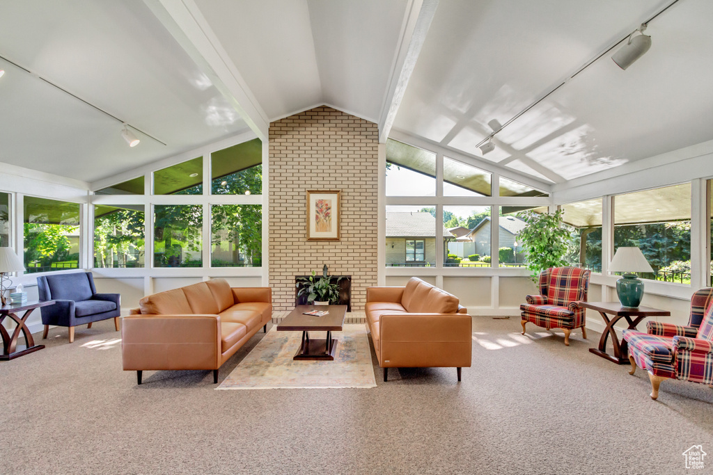 Sunroom / solarium featuring a brick fireplace, vaulted ceiling with beams, and rail lighting