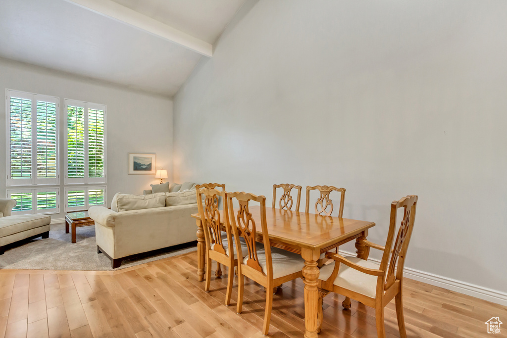 Dining area featuring beamed ceiling, light wood-type flooring, and high vaulted ceiling