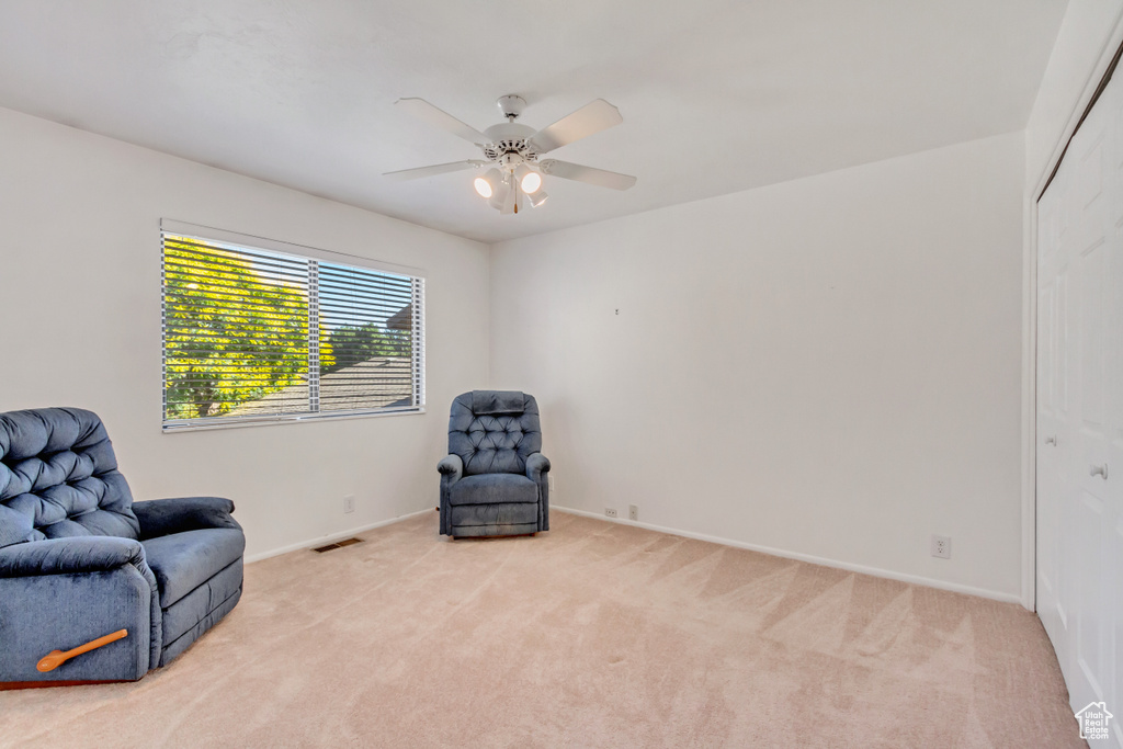 Living area featuring light carpet and ceiling fan