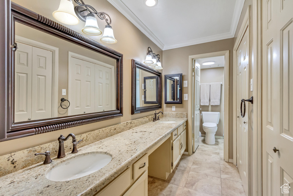 Bathroom with ornamental molding, dual vanity, toilet, and tile patterned floors