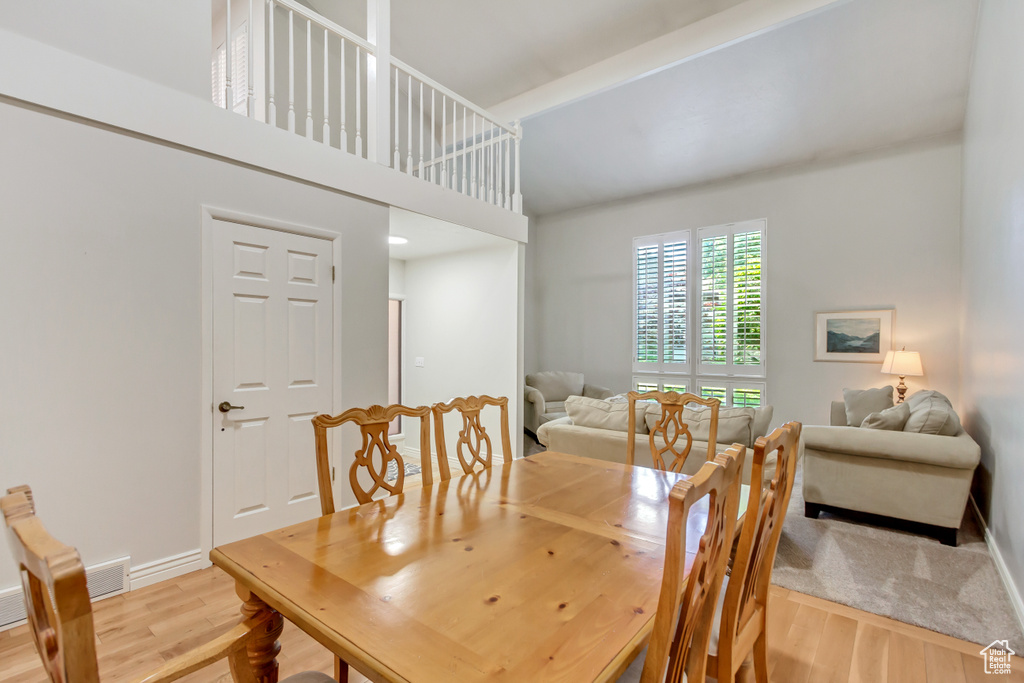 Dining space with light hardwood / wood-style flooring and a towering ceiling