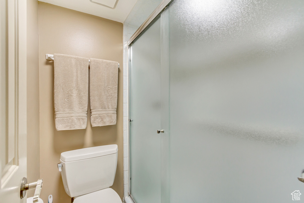 Bathroom featuring toilet, a shower with door, and a textured ceiling