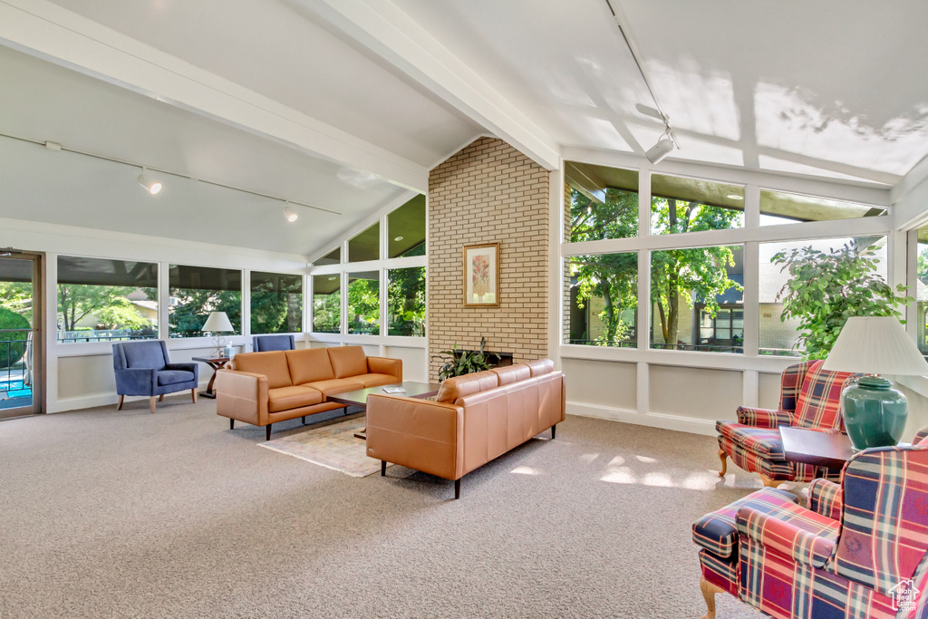 Sunroom featuring plenty of natural light, vaulted ceiling with beams, and track lighting