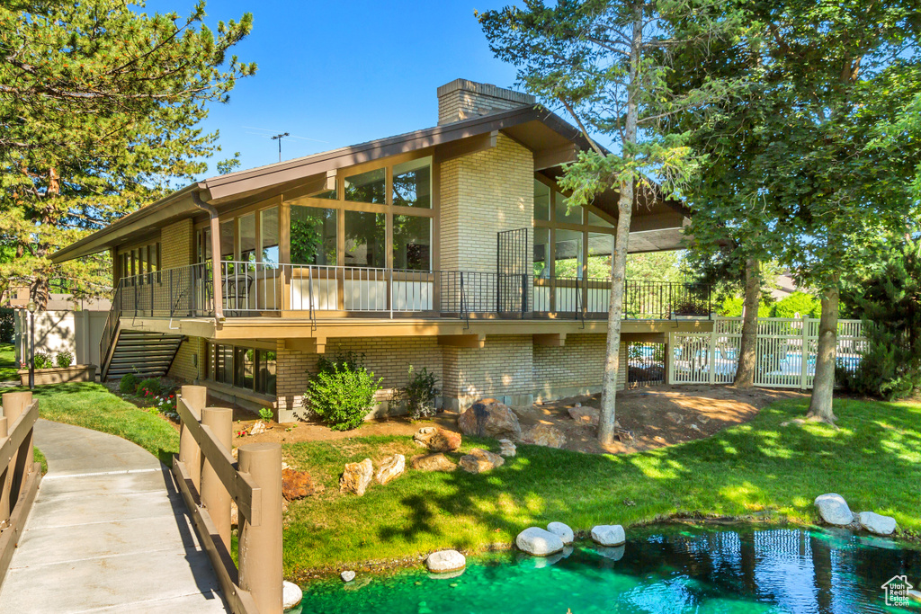 Rear view of property with a deck and a yard