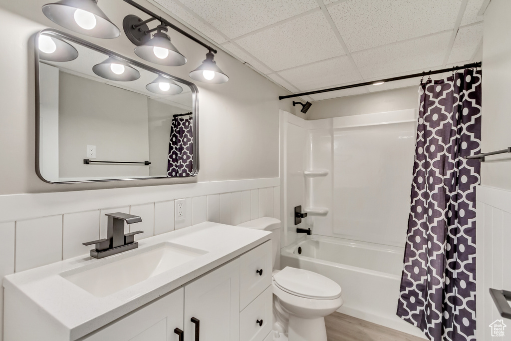 Full bathroom with vanity, hardwood / wood-style floors, shower / bath combo with shower curtain, a paneled ceiling, and toilet