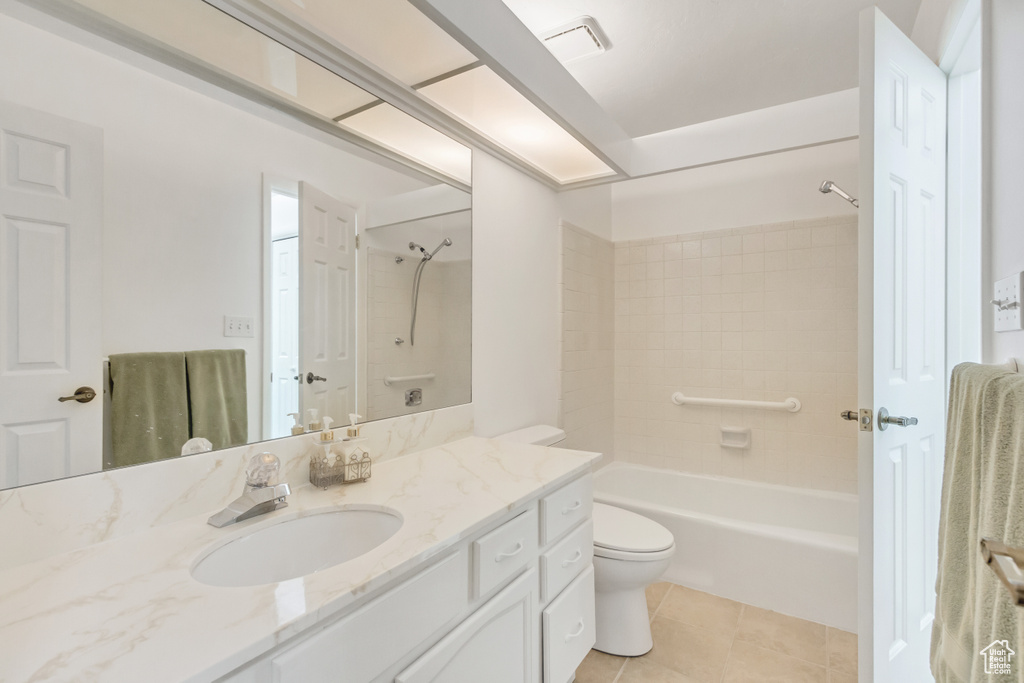 Full bathroom with tiled shower / bath combo, vanity, tile patterned floors, and toilet