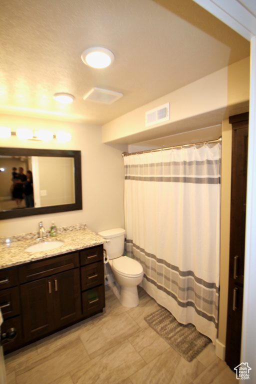 Bathroom featuring tile patterned flooring, toilet, and vanity