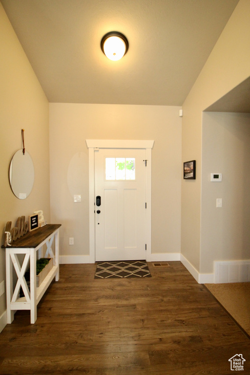 Foyer entrance with vaulted ceiling and dark hardwood / wood-style flooring